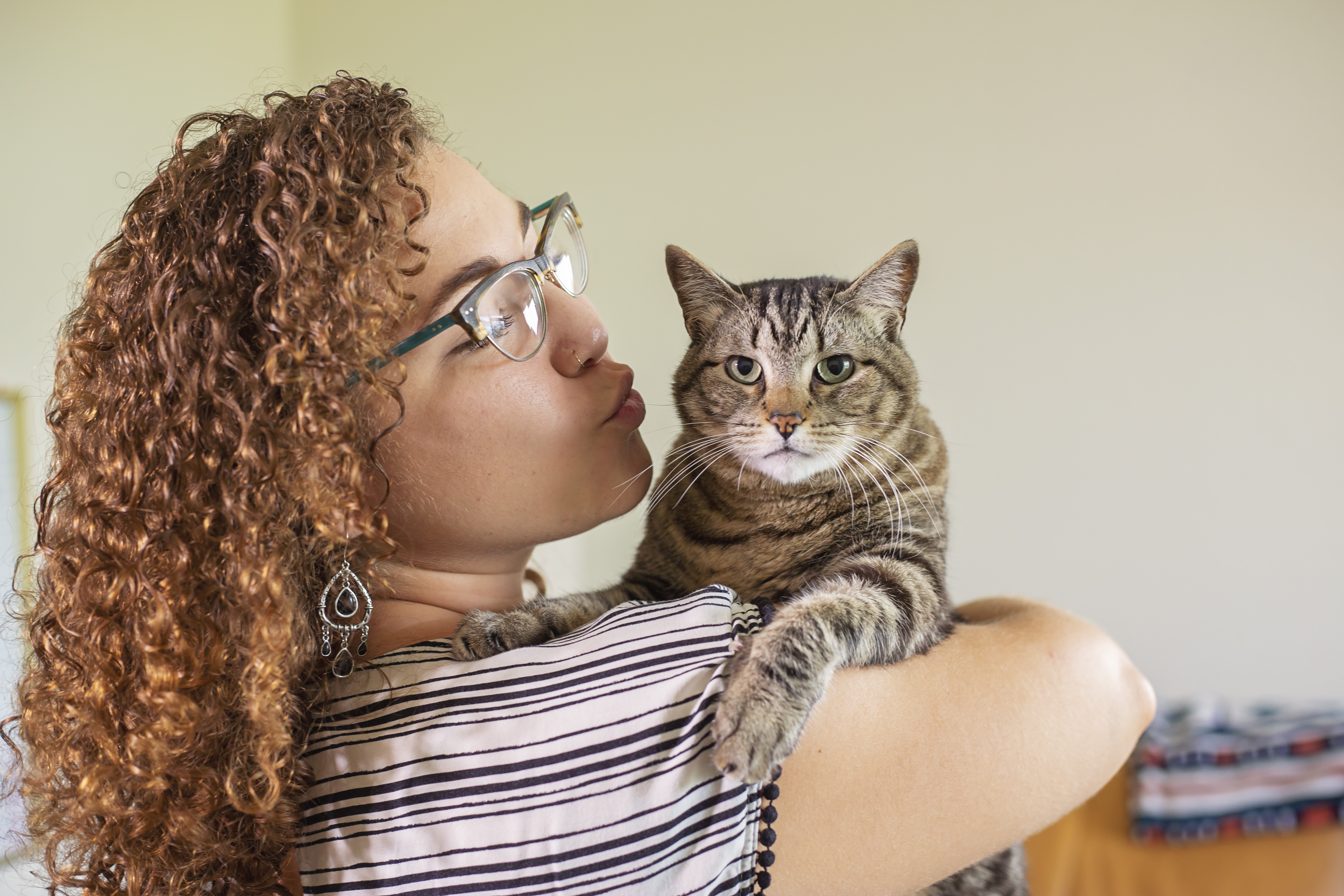 A girl gives her cat a kiss on the cheek.